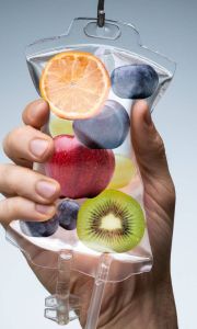 Mano che stringe una sacca per terapia intravenosa piena di fette di frutta